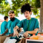 Young woman organizing donation boxes and talking to volunteers outdoors